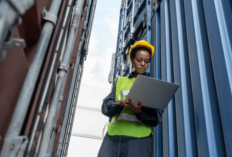 Young African American woman worker at overseas shipping container yard . Logistics supply chain management and international goods export concept .