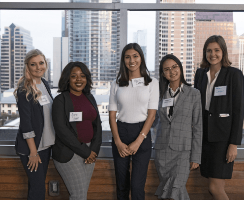 Five young women posing for photo at a UCREW event with buildings in background