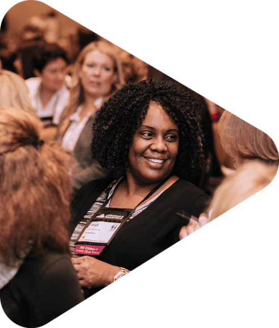 woman sitting in audience smiling at another woman