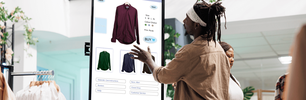 Customer using touch display shopping for fashion items in clothing store, interactive board. African american man choosing stylish clothes with different designs, modern kiosk service.