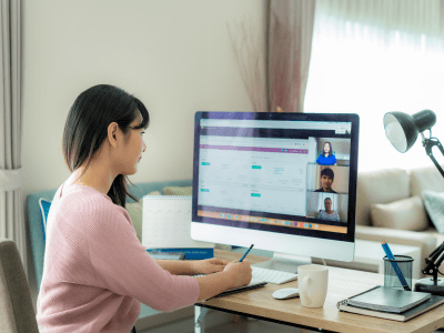 Back view of Asian business woman talking to her colleagues about plan in video conference. Multiethnic business team using computer for a online meeting in video call. Group of people smart working from home.