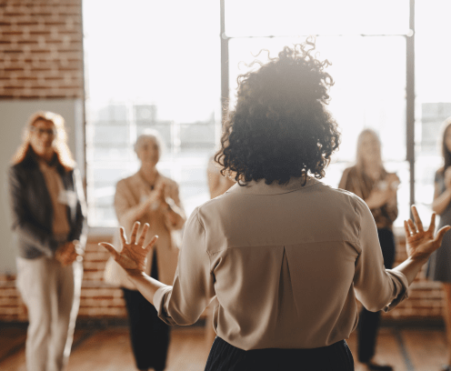 Businesswoman with arms outstretched talking to a small group