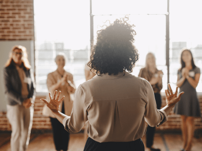 Businesswoman with arms outstretched talking to a small group
